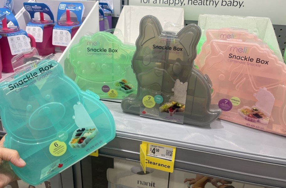 3 snackle boxes on a store shelf with a womns hand holding up a 4th