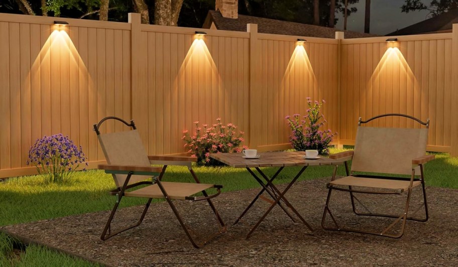 solar fence lights behind a patio set in a backyard.