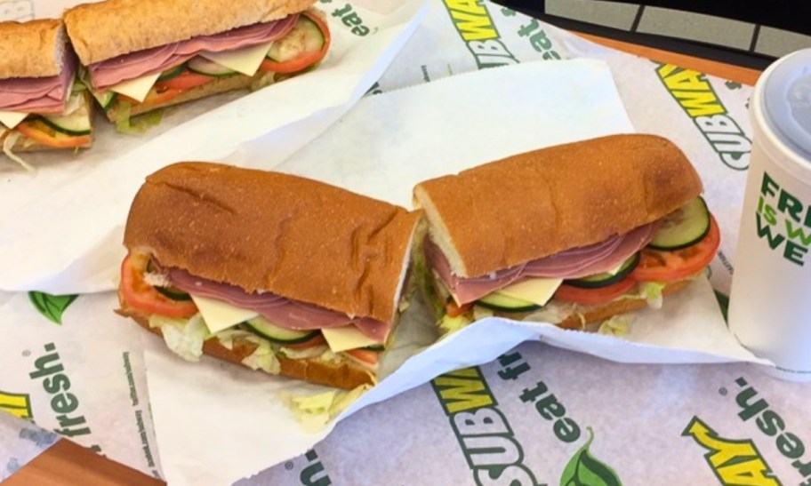 a footlong subway sandwich on a table next to a drink