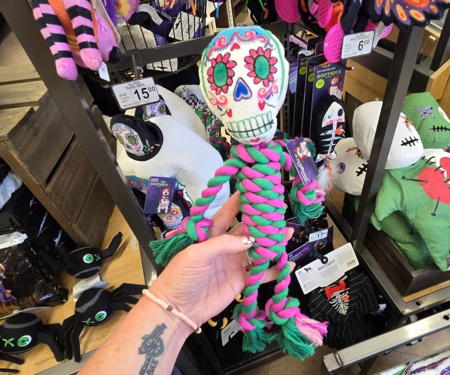 a womans hand holding a day of the dead sugar skull rope dog toy