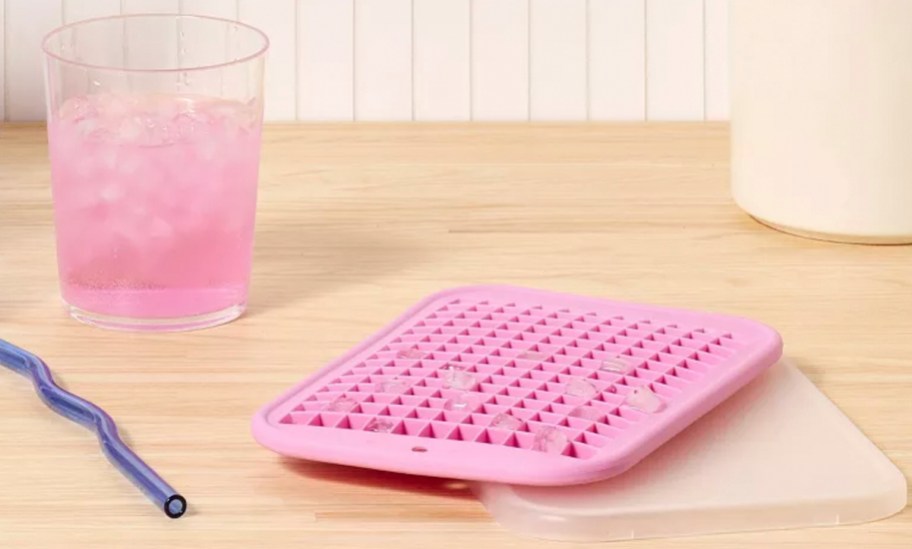 pink ice tray with drink next to it on table