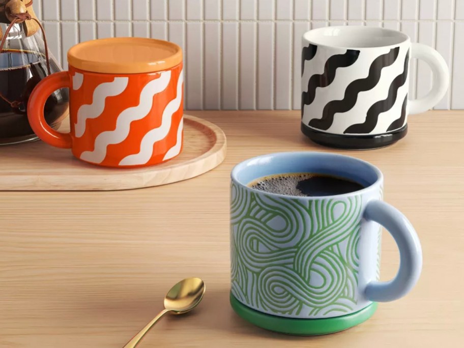 orange, blue and black stoneware squiggle mugs on table