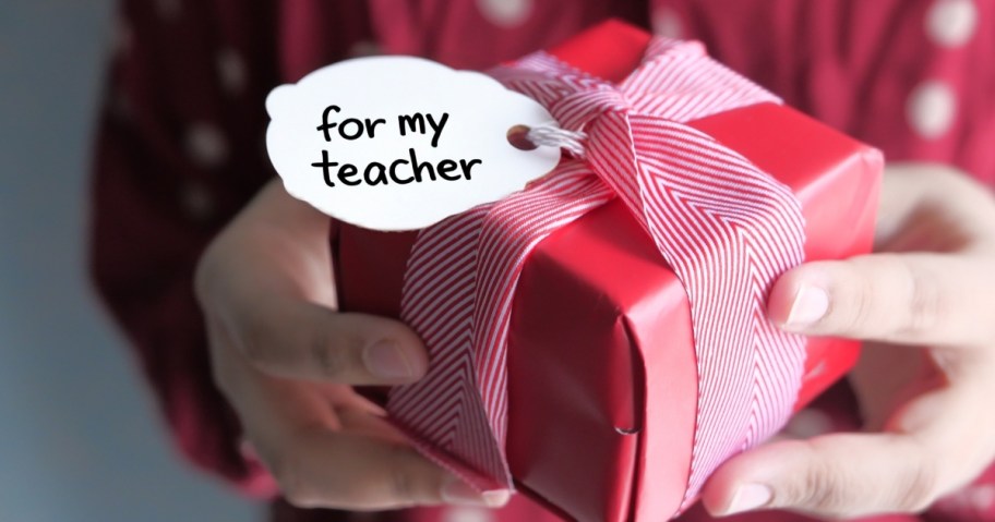 person holding red wrapped gift with for my teacher gift tag