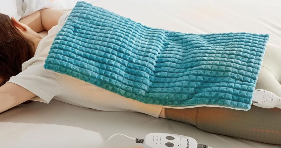 woman laying down with teal heating pad laid on her back