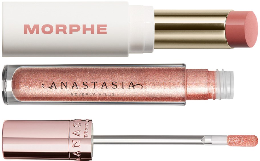 A Morphe lipstick and a sparkly Anastasia Beverly Hills lip gloss tube with its wand applicator laid horizontally.