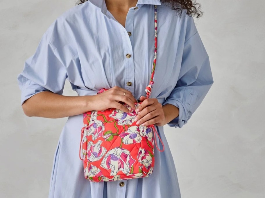 woman wearing a blue dress and carrying a pink floral crossbody bag