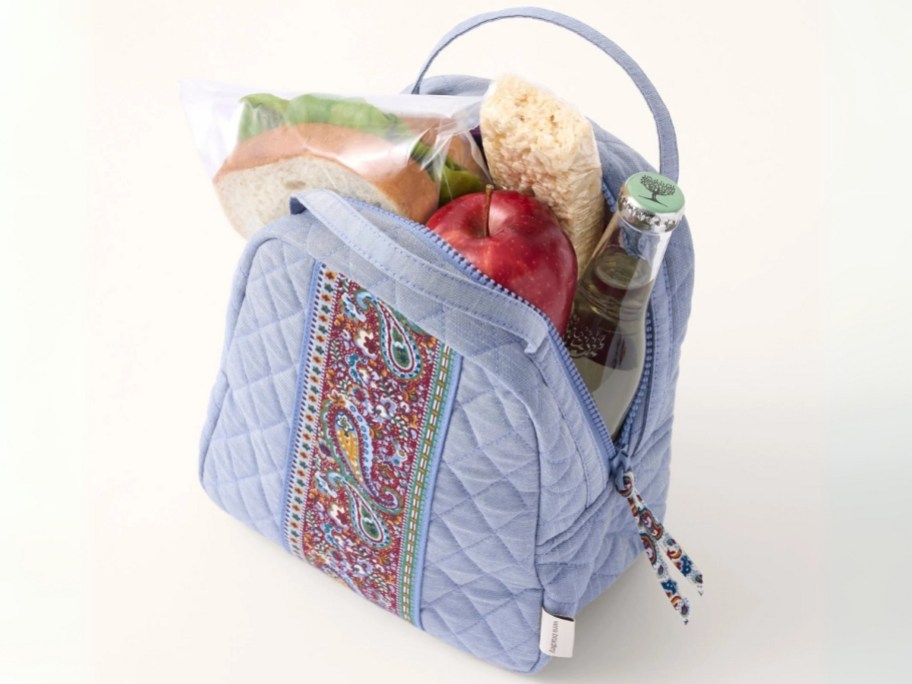 a blue and paisley lunch bag with the top open showing food in it