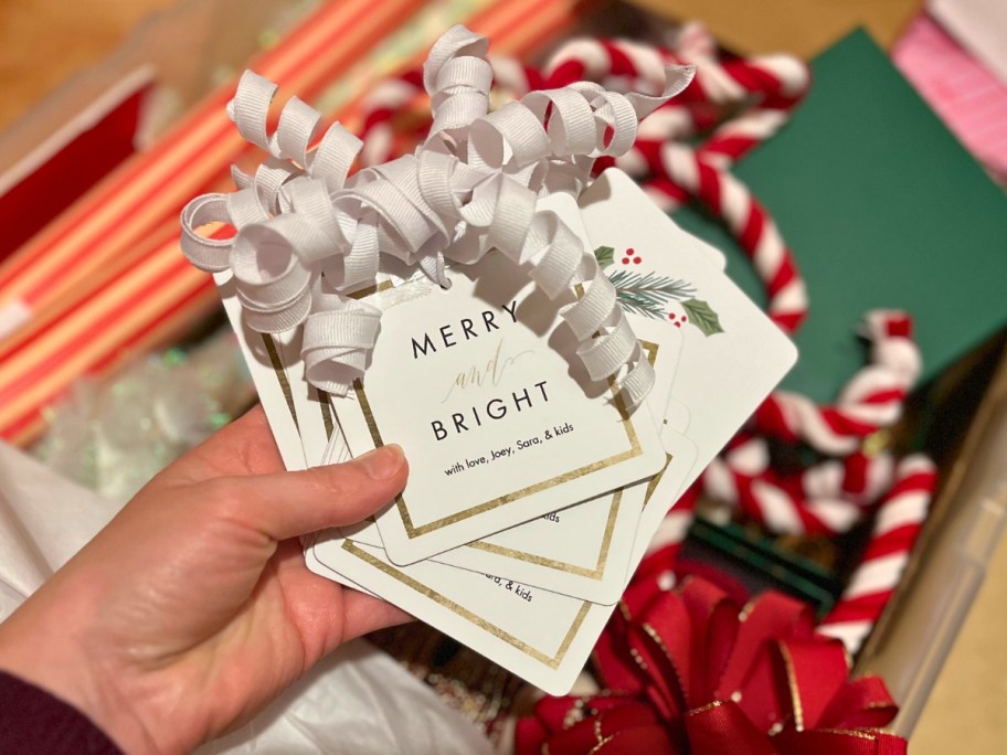 hand holding custom photo coasters with Merry & Bright holiday theme, ribbon and bows around them