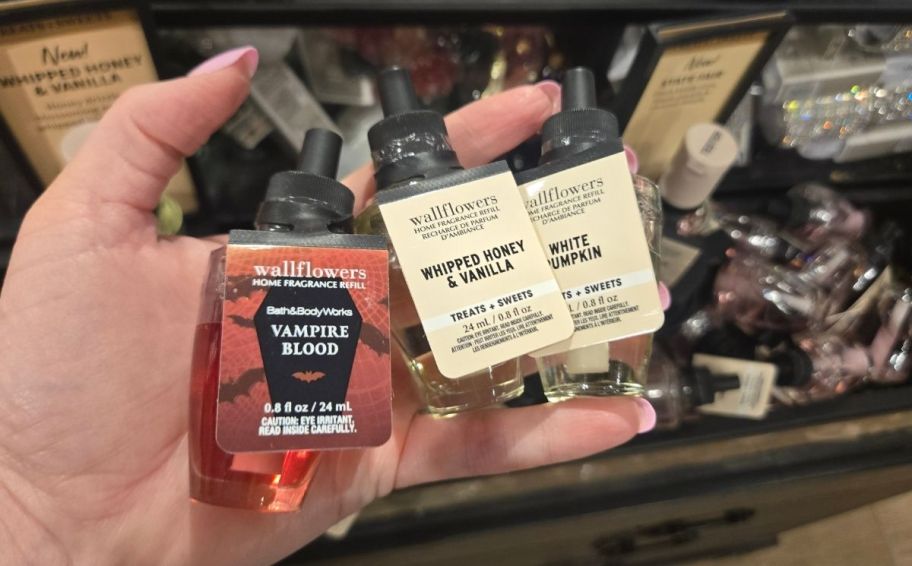 womans hand holding 3 wallflowers refills