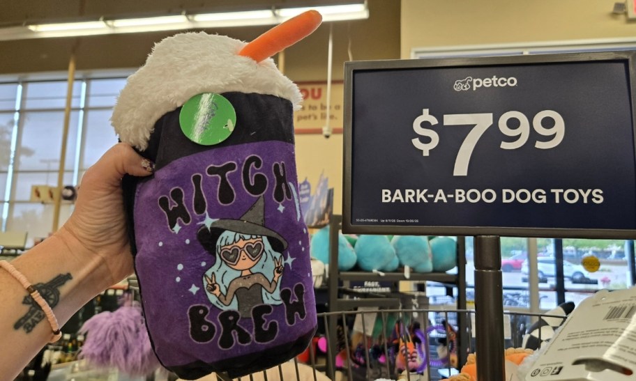 a womans hand holding a plush dog toy