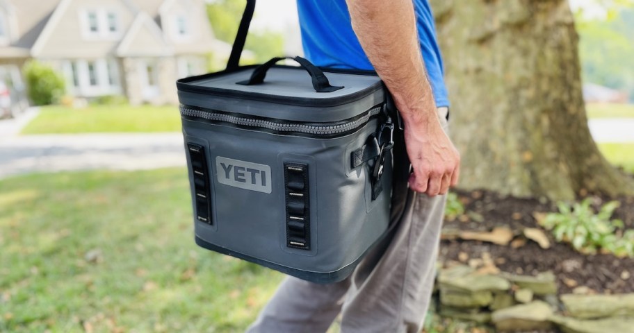 man walking outside with gray yeti cooler on shoulder