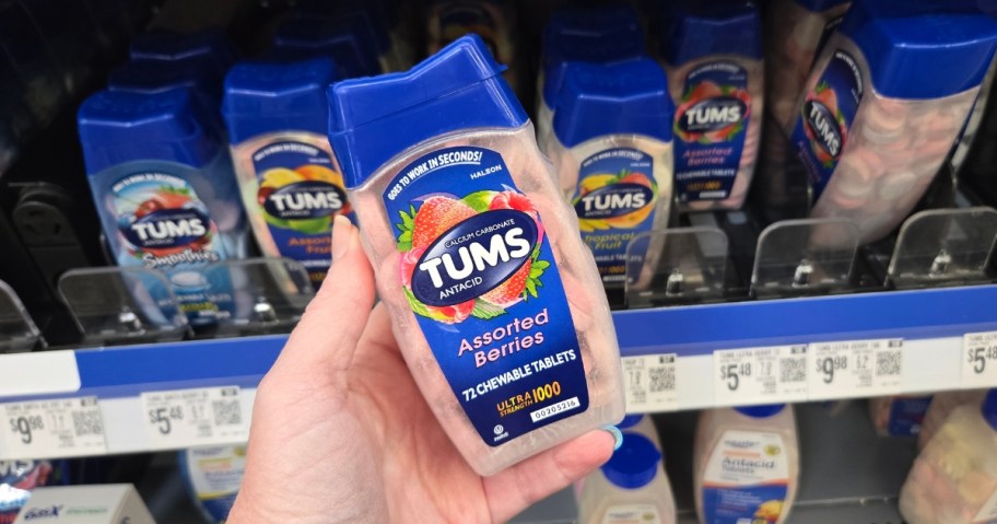 hand holding a bottle of Tums, more on a store shelf behind it