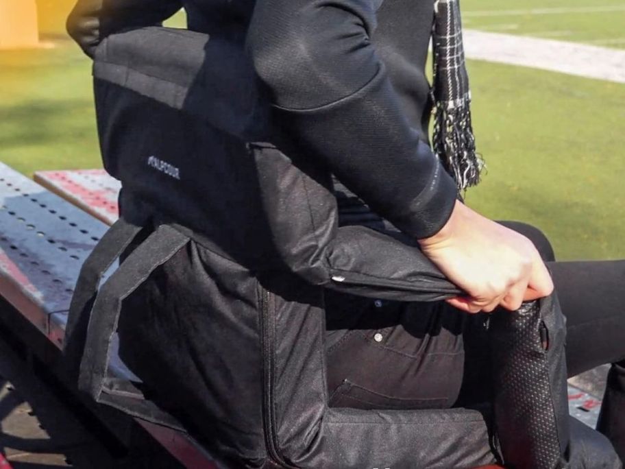 A person sitting in a black padded chair in a stadium