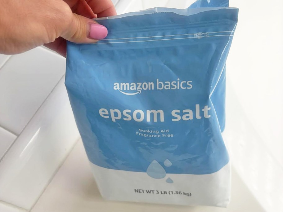 hand holding a blue bag of Amazon Basics Epsom Salt