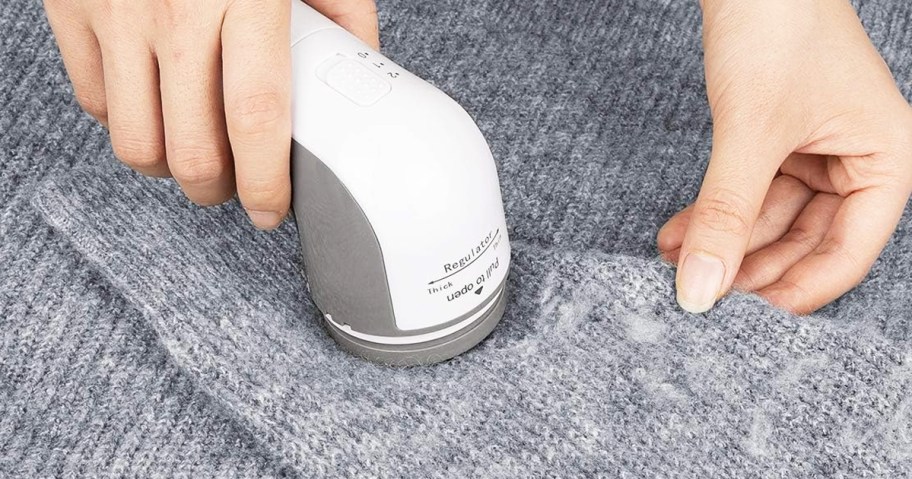 using a fabric shaver on a grey sweater