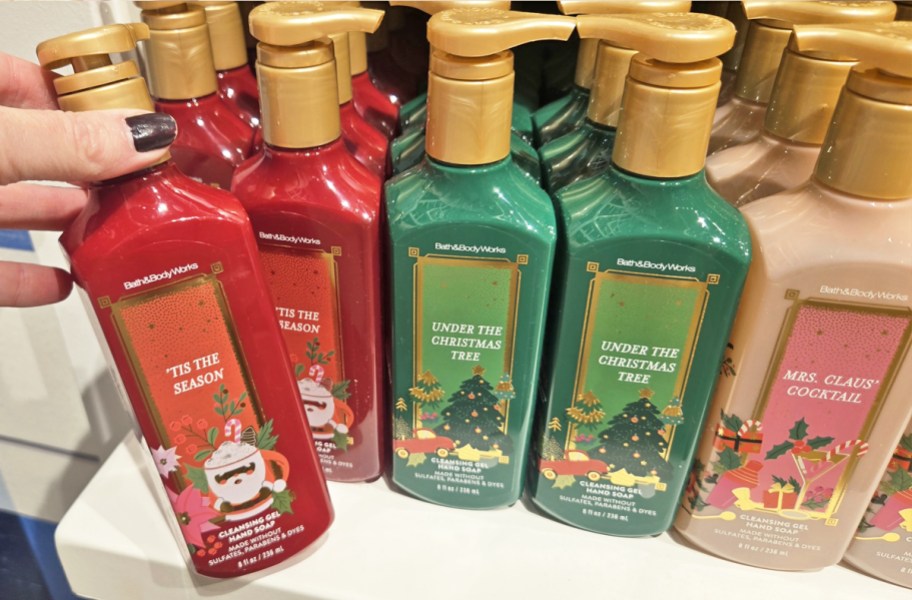 hand grabbing christmas hand soap from shelf filled with more soaps