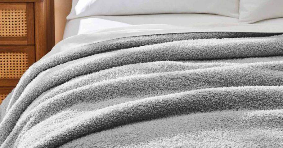 A bed with a gray soft blanket on it 