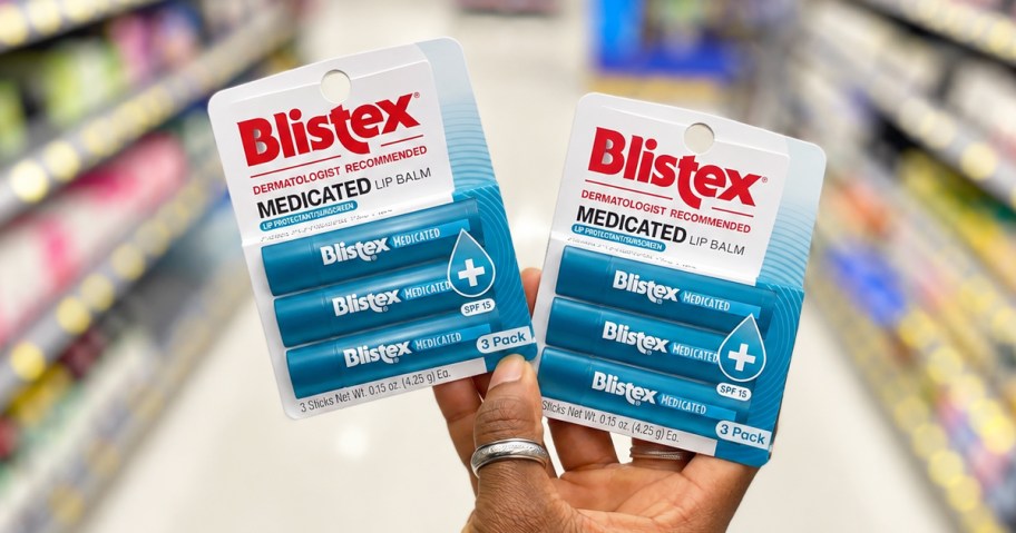hand holding up two packs of Blistex Lip Balms in store aisle