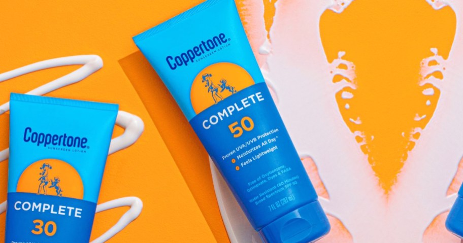 blue bottle of Coppertone Complete Sunscreen on an orange background with smears of sunscreen