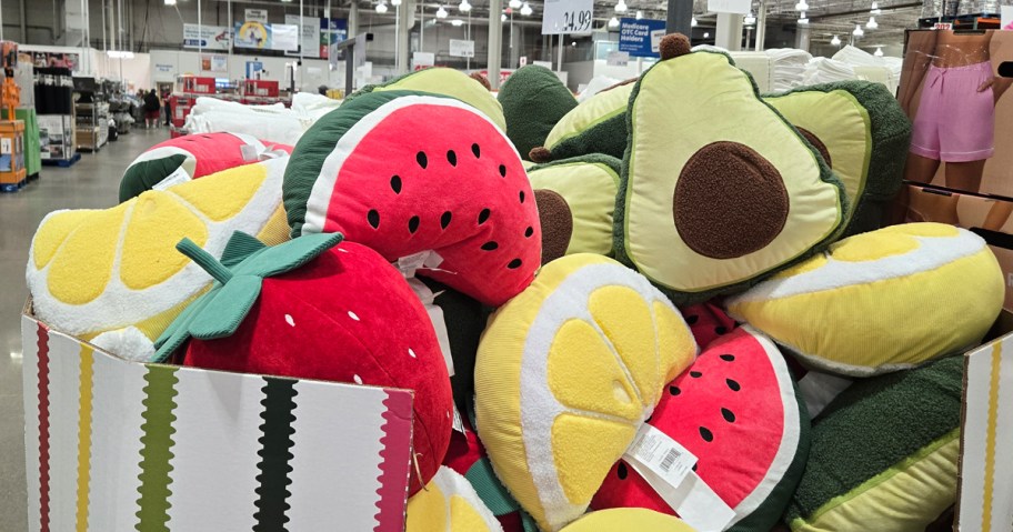 pile of fruit shaped pillows in display box at costco