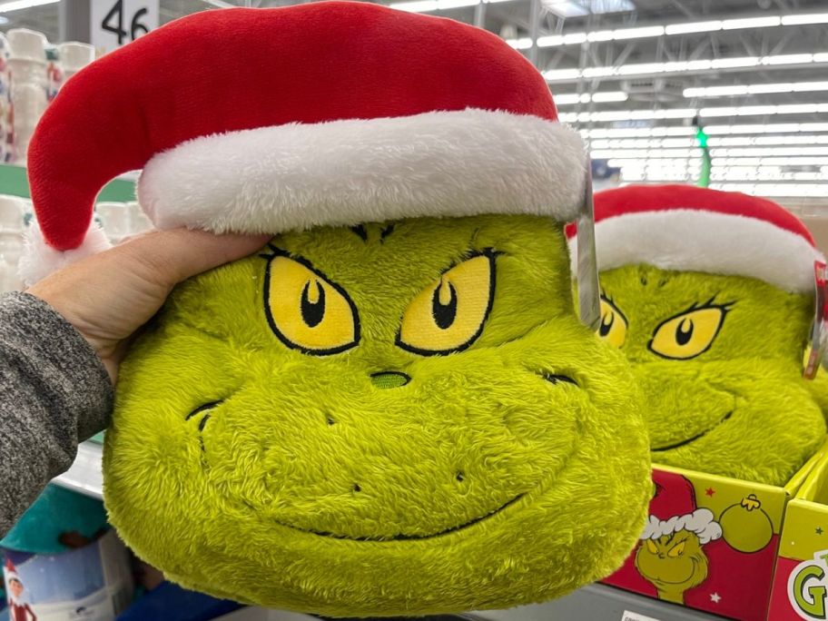 Woman holding grinch throw pillow 