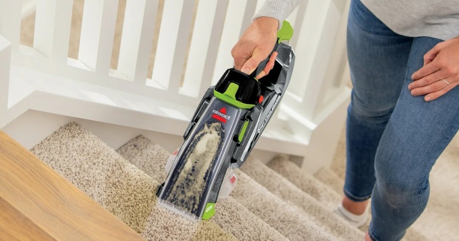 woman using a Bissell Cordless Pet Stain Eraser on carpeted stairs