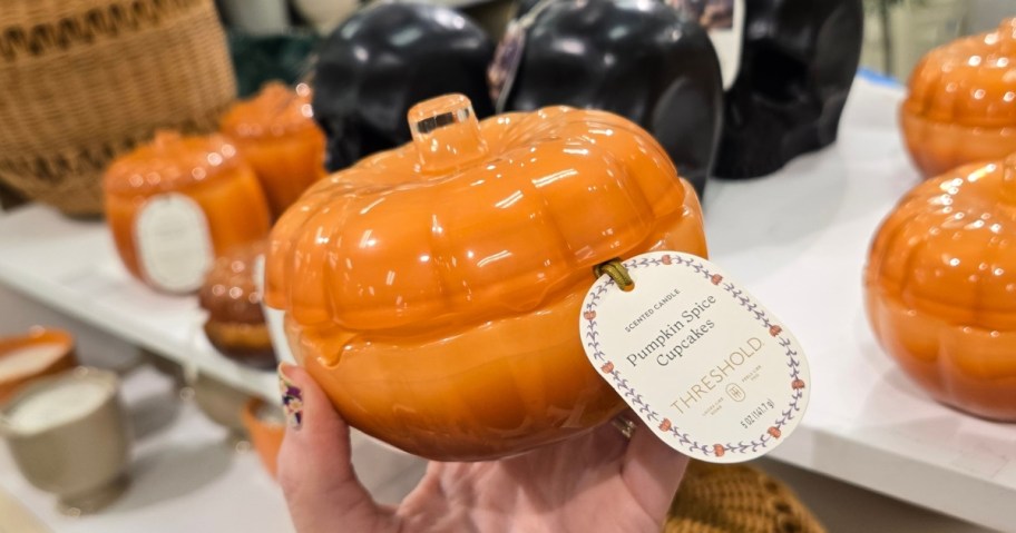 hand holding a glass pumpkin shaped jar candle
