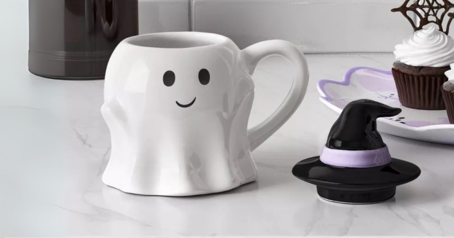 a ghost shaped coffee mug with a witch hat lid on a kitchen counter