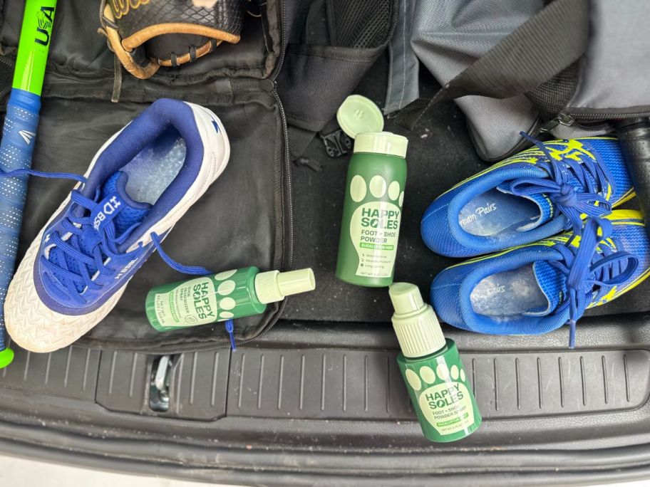 Athletic shoes in a trunk with three bottles of Happy Soles Sprays and Powders.