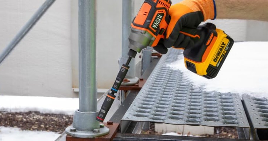 person using an orange impact driver with a reversible socket set
