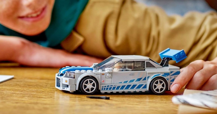 boy playing with LEGO Speed Champions 2 Fast 2 Furious Nissan Skyline GT-R on table