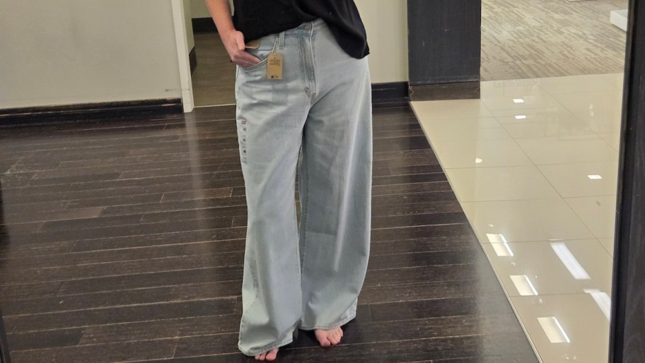 woman taking selfie in store mirror with light denim