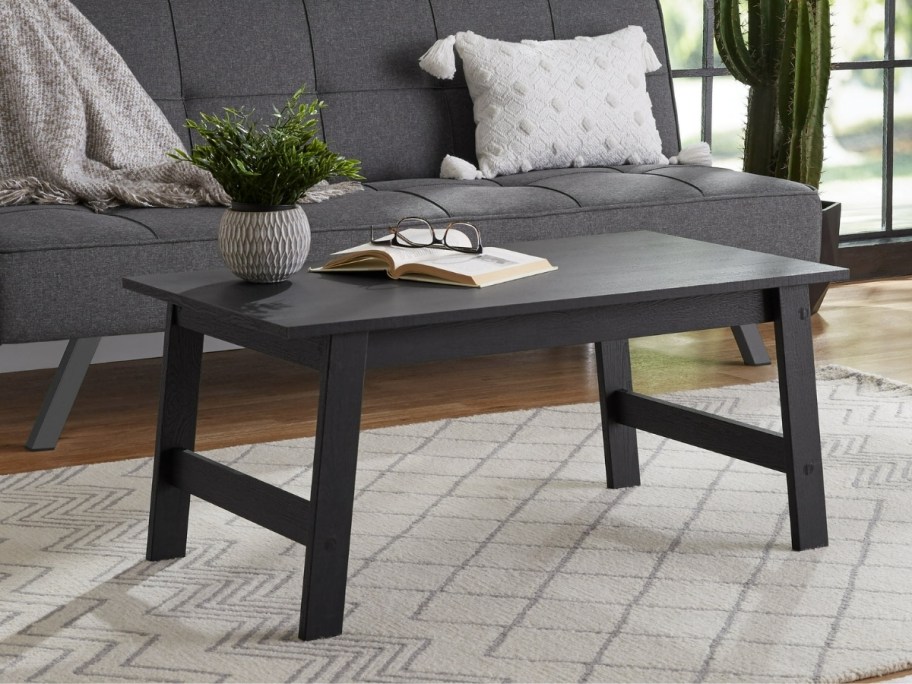 a black coffee table in front of a small sofa