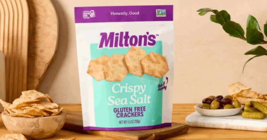 A bag of crackers on a table with other snacks surrounding it