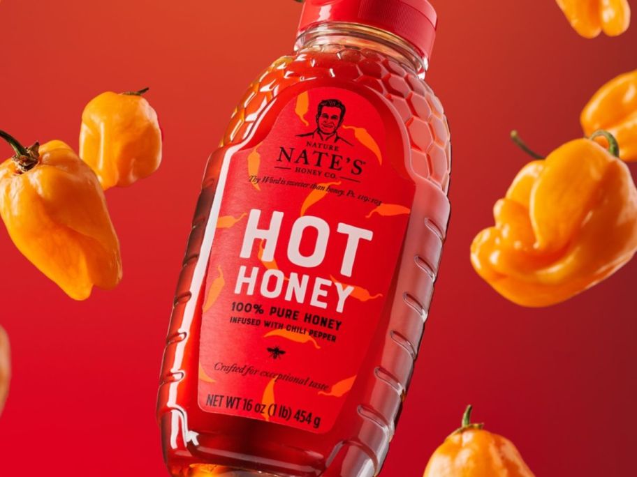 A bottle of Nate's Hot Honey surrounded by habanero peppers