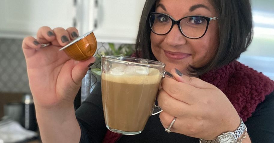 woman holding a cup of nespresso and a coffee capsule