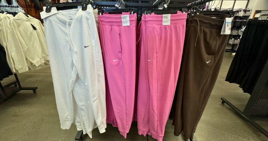 nike sweatpants and joggers in different colors hanging on rack in store