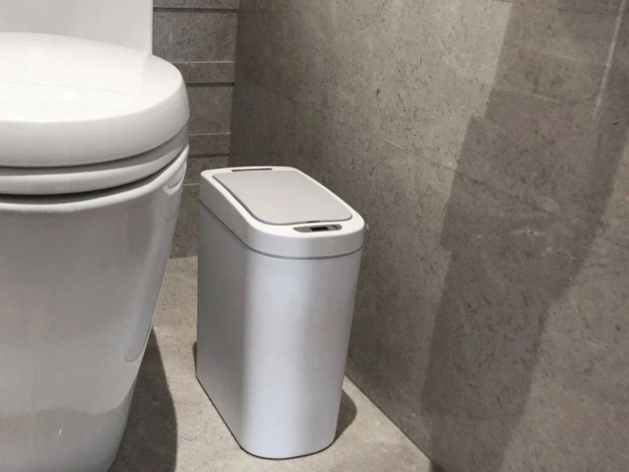 automatic motion sensor trash can by toilet in bathroom