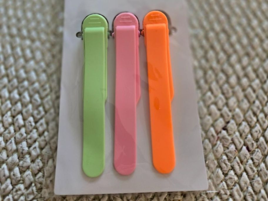 3 plastic automatic bookmark clips in green, pink, and orange