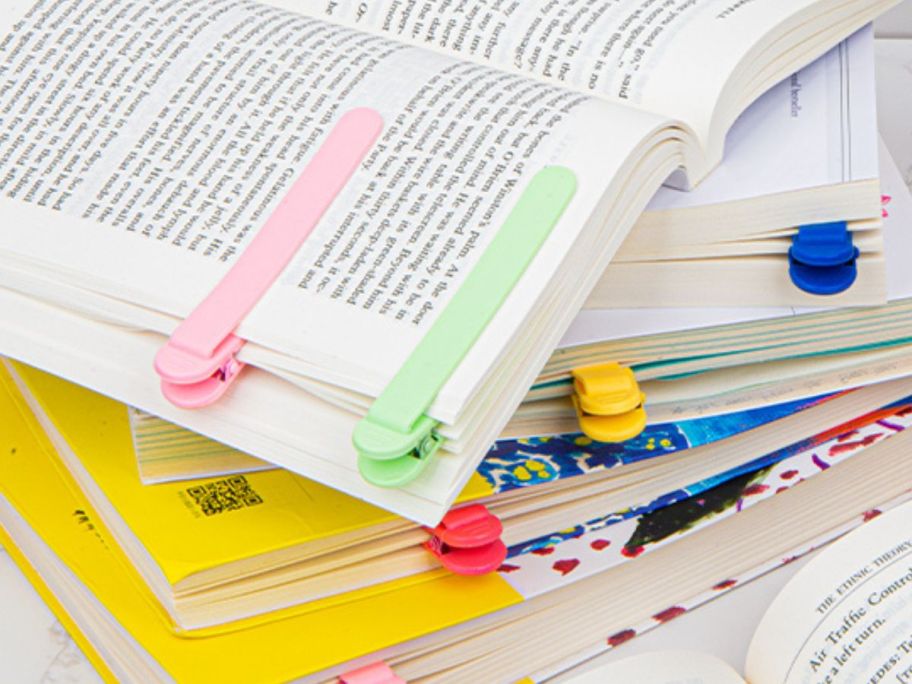 Several books containing plastic automatic bookmark clips in various colors 