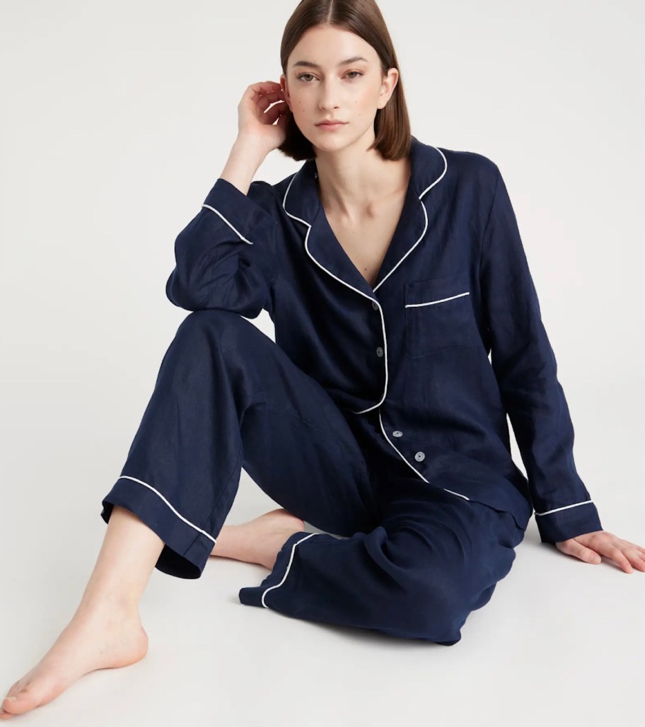 woman sitting in navy pajamas set with white pinstripe