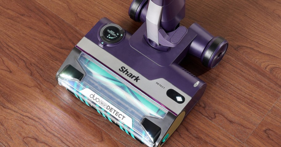 A purple Shark vacuum cleaner head on a wooden floor.