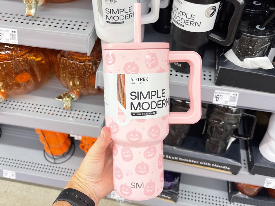 hand holding up a pink pumpkin print tumbler in store