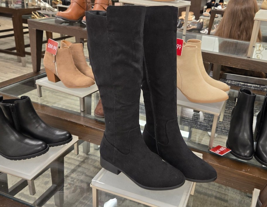 pair of tall black boots on store pedestal