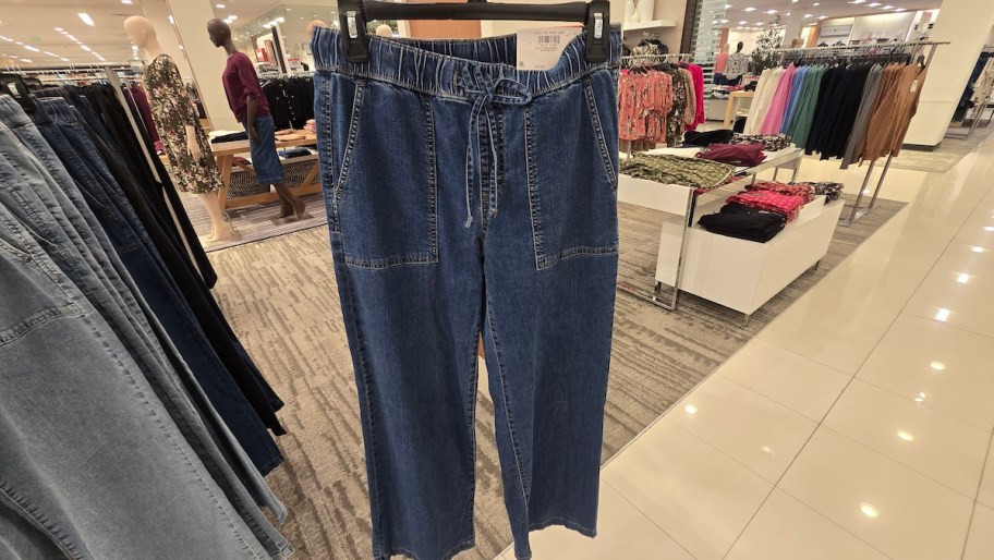 pair of denim pants hanging on hanger in store