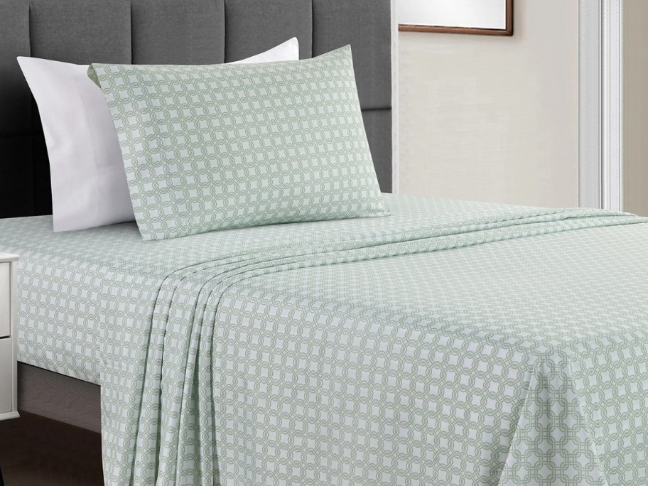 a bed made with a set of green and white geometric print sheets