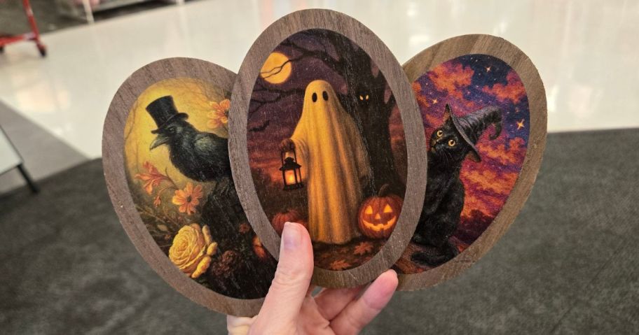 Hand holding 3 wooden Halloween Pictures