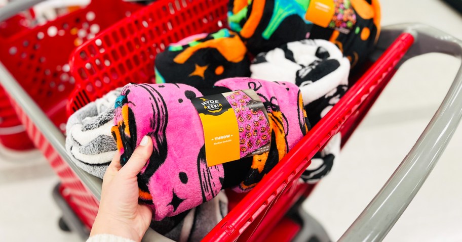 hand grabbing a pink halloween throw blanket from red target shopping cart
