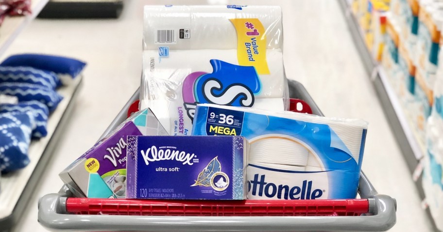 multiple packs of toilet paper and facial tissue in red shopping cart