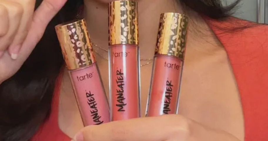 Woman holding 3 Tarte maneater cheek plump blush